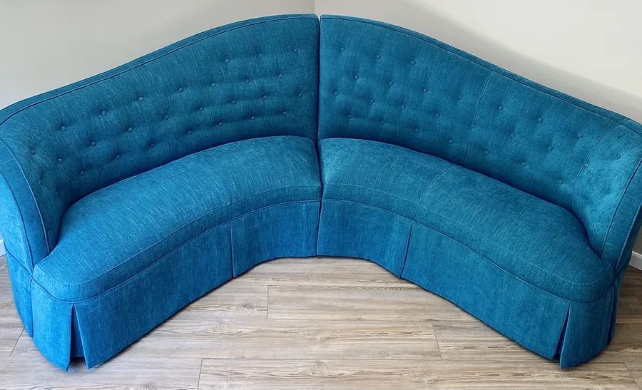Corner banquette upholstered in deep teal button-tufted fabric