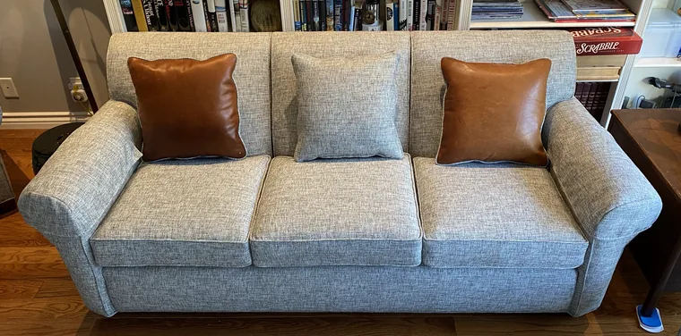 Grey sofa with tan leather accent pillows