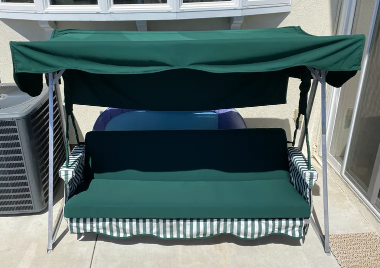 Porch swing with a new green canopy and cushion